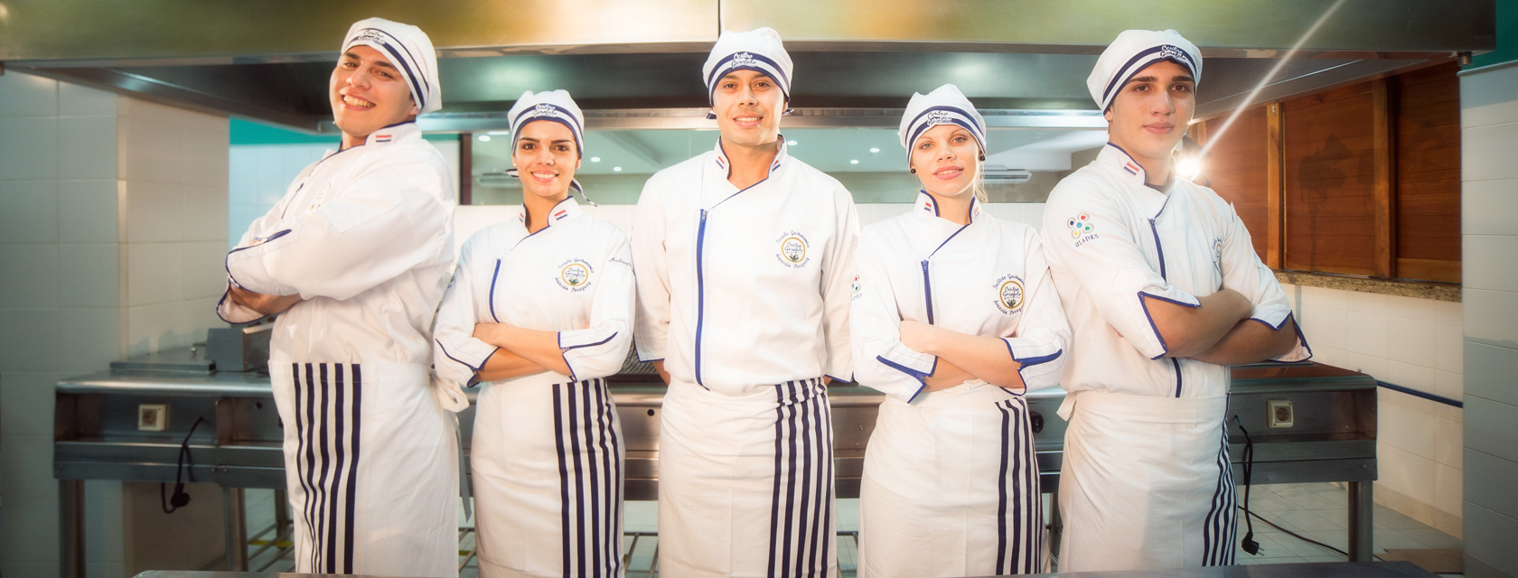 Grupo de cinco alumnos del Centro Garófalo, con uniforme y delantal de la escuela, posan con orgullo en la cocina.