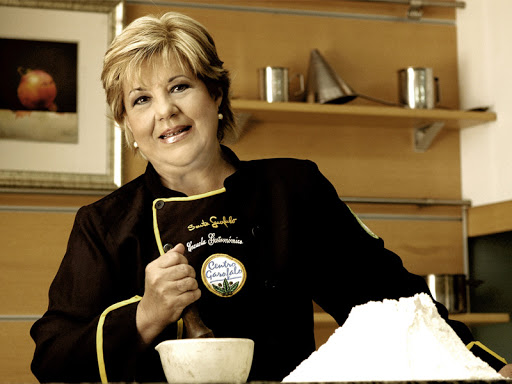 Sarita Garófalo, chef y directora, con la chaqueta del Centro Garófalo junto a un montículo de harina en la cocina.